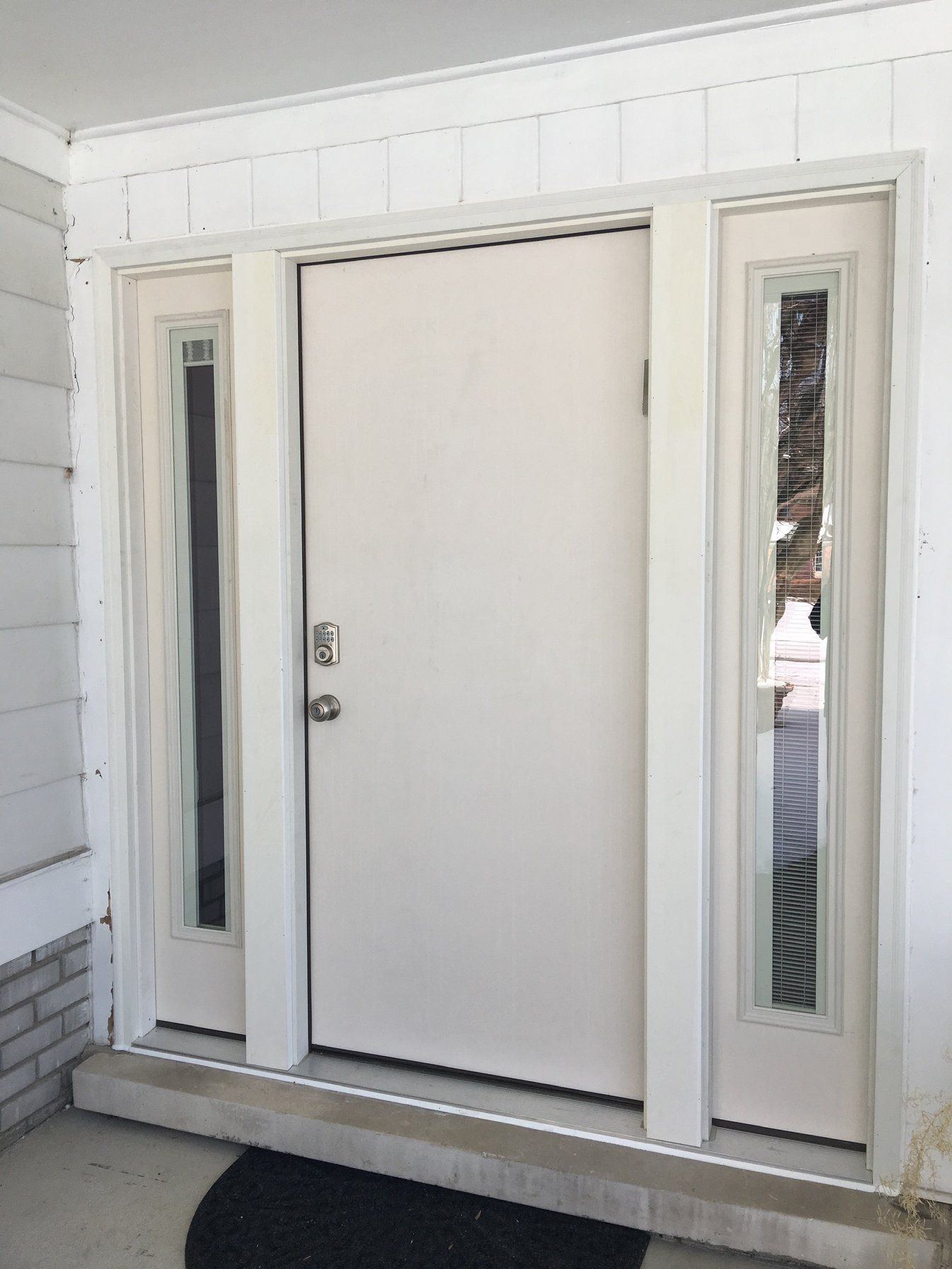 Solid white entry door with two narrow frosted glass sidelights on the same porch
