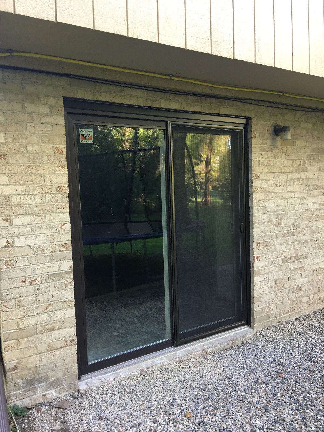New black-framed sliding patio door in the same light brick opening
